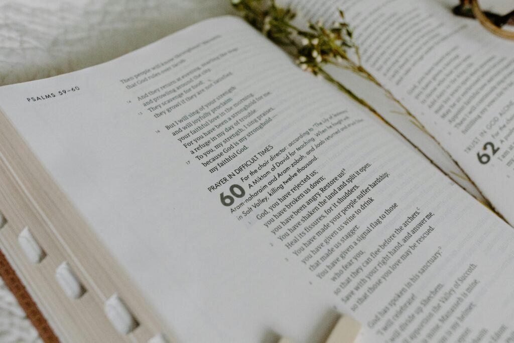 Close-up of an open Bible showing Psalm 60 with dried flowers.
